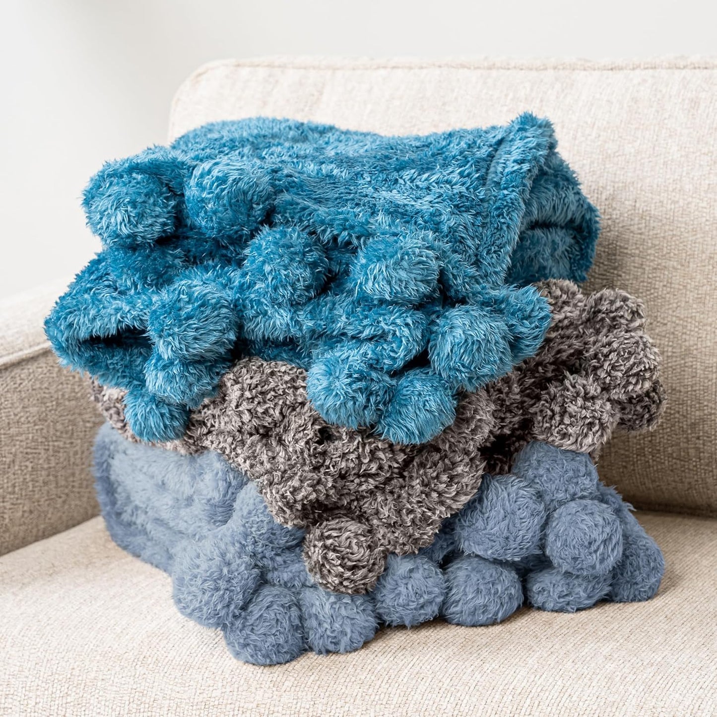 Blue and gray textured blanket draped over a beige couch