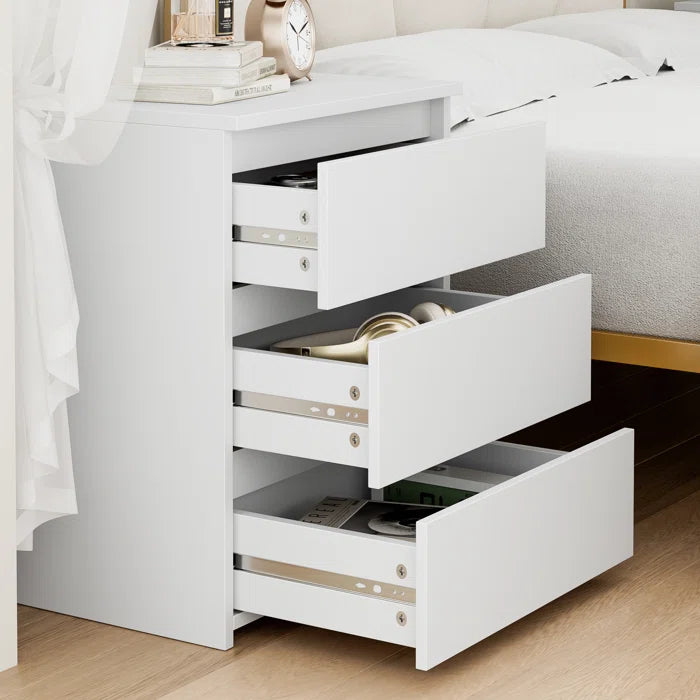 White nightstand with three drawers in a dorm room setup.